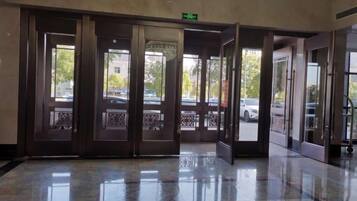 A hotel lobby with a marble floor, a set of revolving doors, and a view of the street outside.