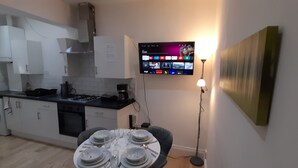 A modern kitchen with white cabinets, a built-in oven, and a dining area with a table set for four. - Privet apartment with 2 bedrooms for relaxing escape in EastHam near CentralPark (London)