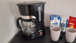 A coffee maker, two white cups, a box of milk, and two packets of sugar and cream. - Privet apartment with 2 bedrooms for relaxing escape in EastHam near CentralPark (London)