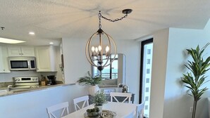 A spacious kitchen with white cabinetry, a central island with seating, and a chandelier. - Oceanfront Escape! Stylish 3 bedroom corner unit (North Myrtle Beach)