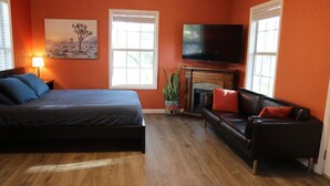 A bedroom with a bed, a sofa, a fireplace, and a TV. - Austin Cabin (Austin)
