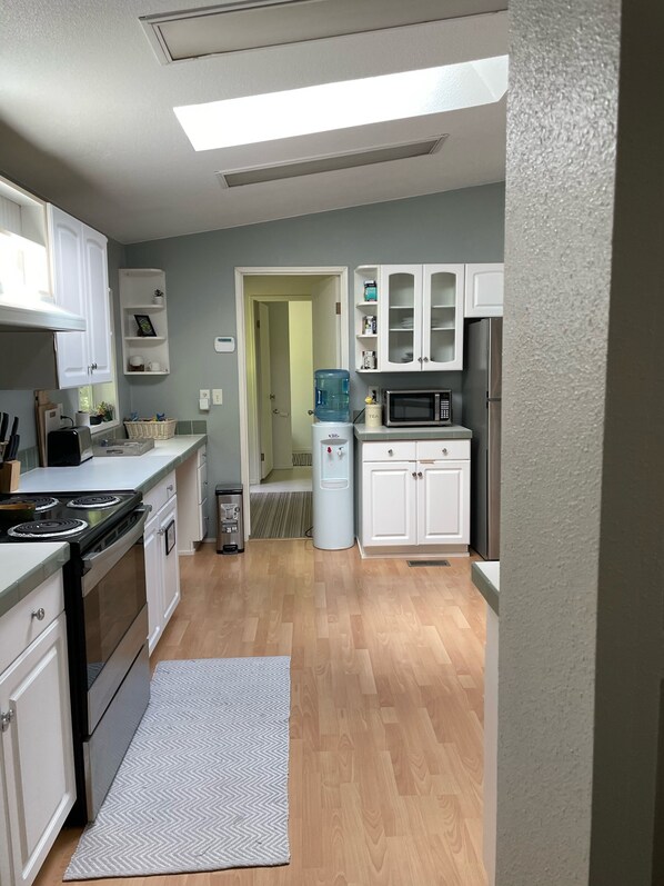 A modern kitchen with white cabinets, a built-in stove, and a water dispenser.