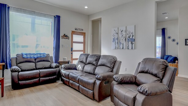A modern living room with a brown leather sofa set, a wooden coffee table, and a ceiling fan. - "Reel Time"  All set up for a family of up to 8! (Denison)