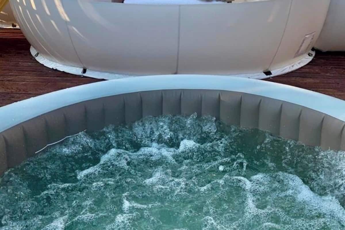 A transparent spherical structure with a bed and curtains, a hot tub in front.