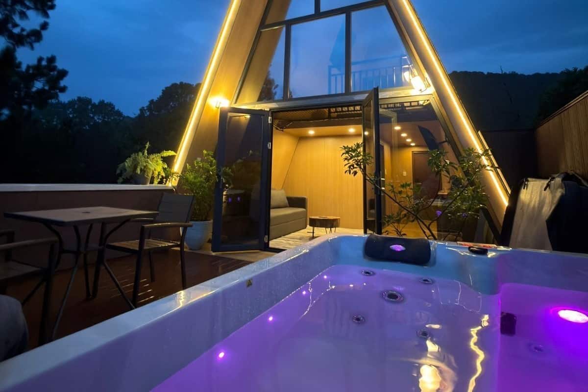 A modern building with a triangular roof, a hot tub, and a patio area with seating.