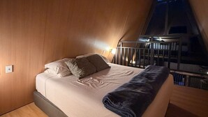 Une chambre à coucher avec un lit, des oreillers, une couverture et une table de chevet avec une lampe.