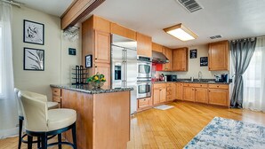 Una cocina moderna con armarios de madera, electrodomésticos de acero inoxidable y una barra.