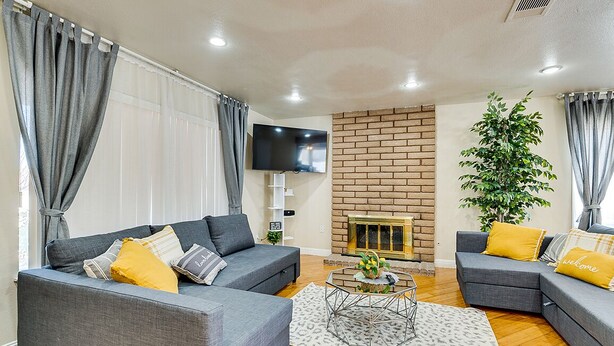 Una sala de estar con dos sofás grises, una mesa de centro, una chimenea y un televisor montado en la pared.