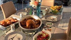 A table set for a meal with a roasted chicken, a bowl of salad, and a plate with a design.