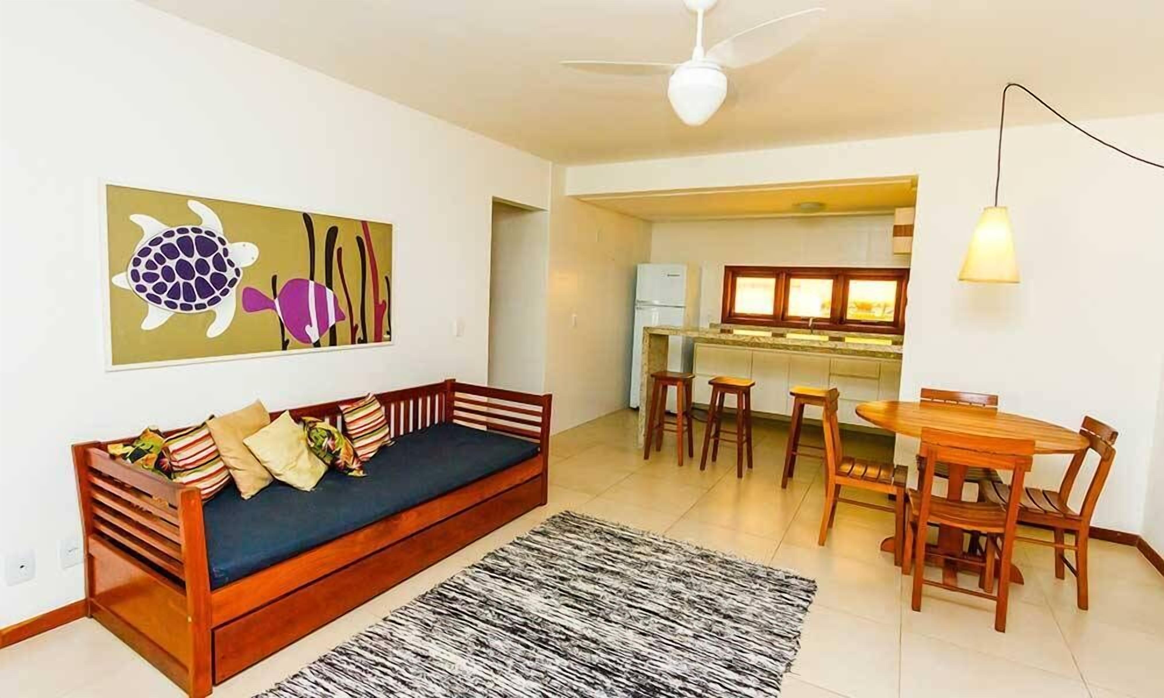 Una sala de estar con sofá, alfombra y comedor con mesa y sillas.