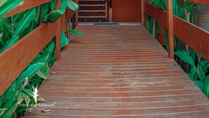 A wooden staircase with a railing, surrounded by large green plants.