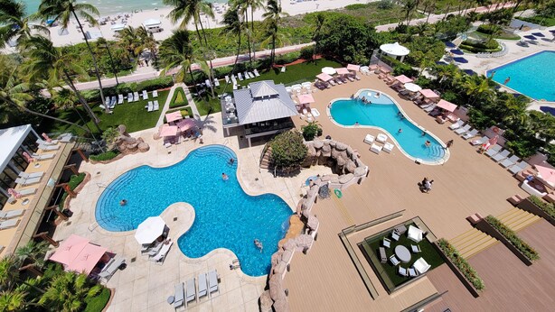 Ein Resort mit mehreren Schwimmpools, Liegestühlen und einem Strandbereich.