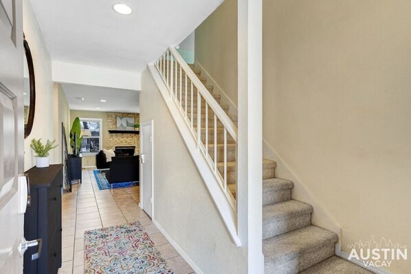Un interior moderno con una escalera, una zona de cocina y un espacio de sala.