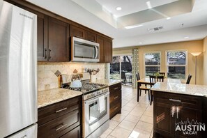 Una cocina moderna con electrodomésticos de acero inoxidable, armarios de madera oscura y una isla grande con encimera de granito.