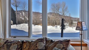 A room with a large window overlooking a snowy landscape and a body of water. - Paging Dr. Powder Condo with Mountain Views on Shuttle Route (Killington)