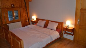 A wooden-framed bed with two bedside tables, each with a lamp. A window with curtains is visible, and a radiator is mounted on the wall. - flat for rent in Les Collons (Thyon-Les Collons)