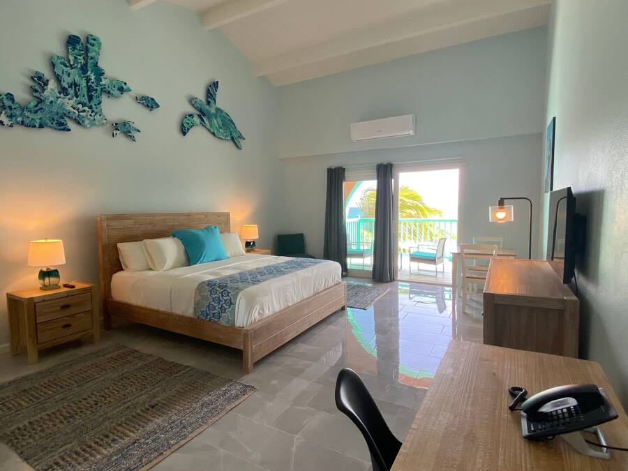 A bedroom with a bed, bedside tables, a desk, a chair, a TV, and a balcony with a view.