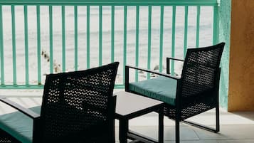 A balcony with two chairs and a table, overlooking the sea.