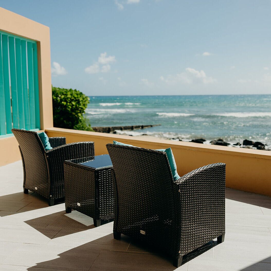 A balcony with wicker furniture and a view of the ocean.