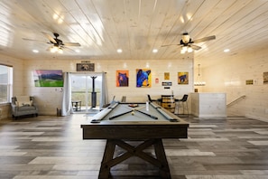 Relax in a well-lit space with a pool table, artworks, and a comfortable armchair.