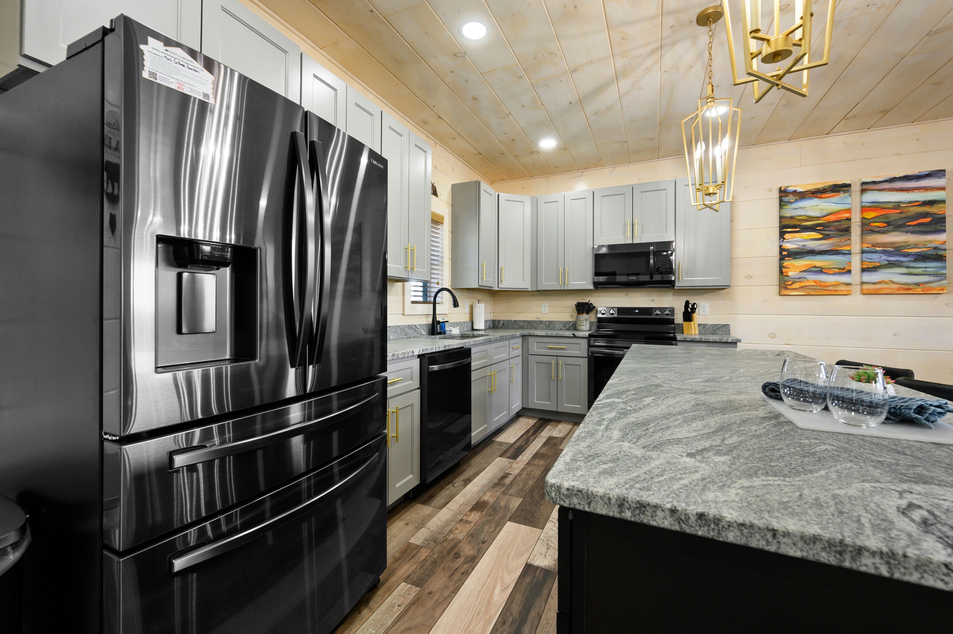 A modern kitchen with stainless steel appliances, grey cabinets, and a granite countertop.
