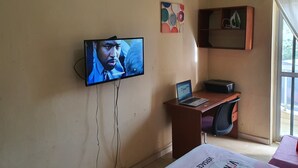A room with a television mounted on the wall, a laptop on a desk, and a window with curtains. - BEDROOM DAKAR PLATEAU (Dakar)