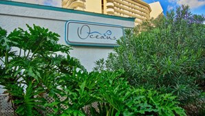 Un cartel de hotel con el nombre 'Oceans' y un edificio al fondo.