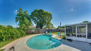 Un jardin avec une piscine, un patio couvert et une clôture en bois.