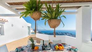Une table à manger dressée pour quatre personnes, avec vue sur la mer et le paysage urbain.