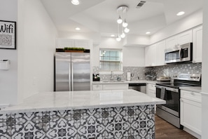 Una cocina moderna con armarios blancos, electrodomésticos de acero inoxidable y un salpicadero con diseño.