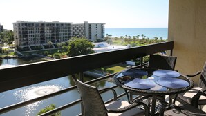 A balcony with wicker furniture, a view of a body of water, and a building in the background. - 2/2 Condo LBK, Pool, Fitness, Tennis (Longboat Key)
