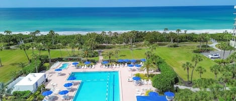 A resort with a swimming pool, lounge chairs, and a view of the ocean.