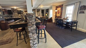 Een ruime keuken met een accentmuur van steen, een eethoek met barstoelen en een woonkamer met open haard.