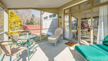 Relax on the patio with a clear view of the surrounding landscape, featuring a round table, comfortable seating, and a beautiful backyard.