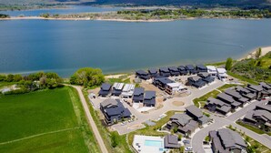 Zona residencial com casas modernas, piscina e um lago grande ao fundo.
