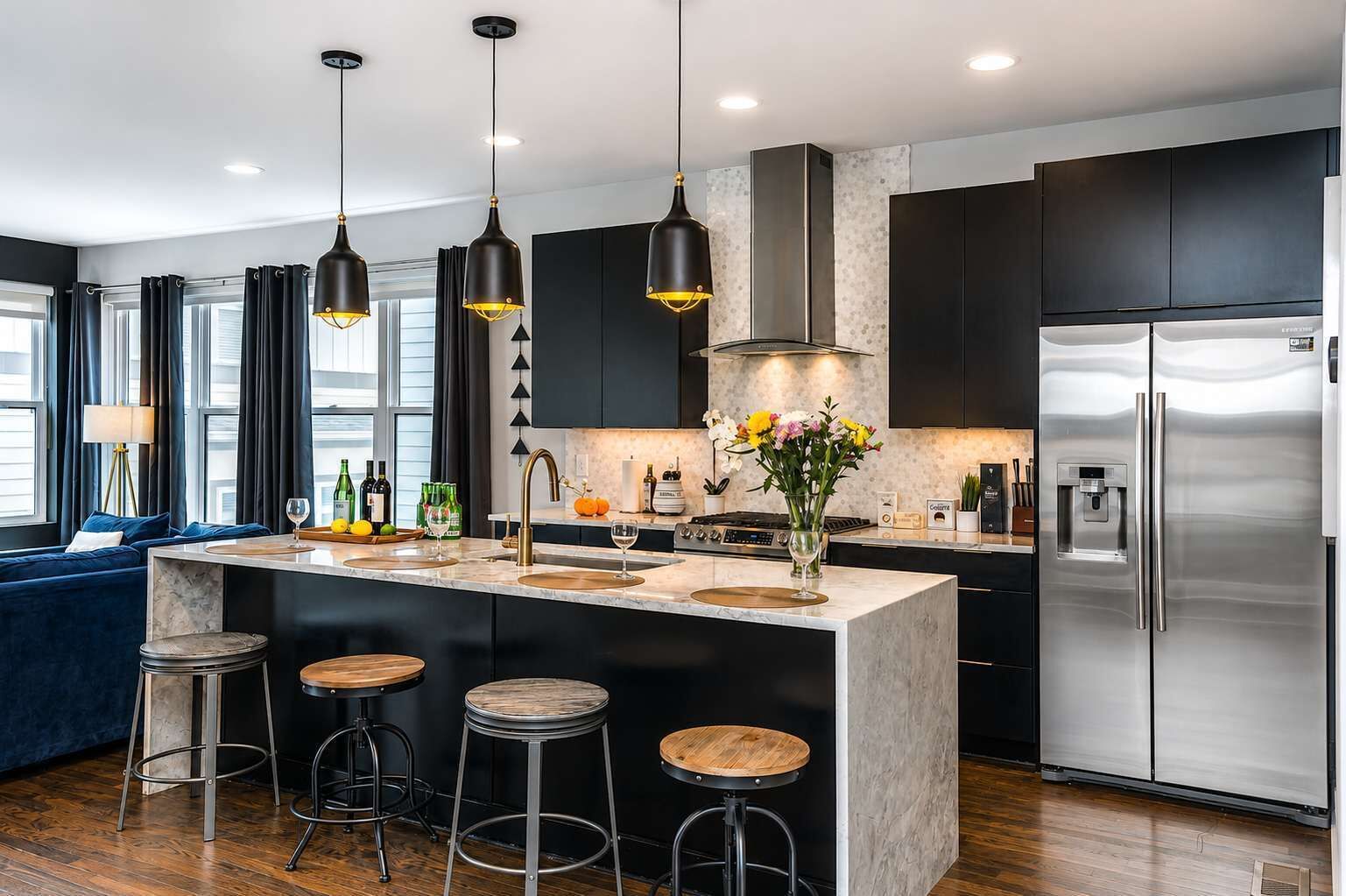 A modern kitchen with a central island, stainless steel appliances, pendant lighting, and a dark color scheme.