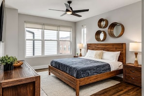 A bedroom with a wooden bed, a ceiling fan, a large window, and a wall-mounted mirror. - Nashville Escape - Gorgeous Home Near Broadway (Nashville)