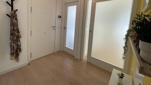 Un pasillo con suelo de madera, puertas blancas y un perchero con una prenda colorida.