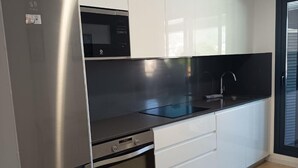 Una cocina moderna con electrodomésticos de acero inoxidable, encimera negra y armarios blancos.