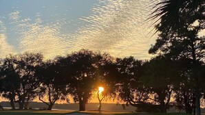 Un campo de golf con un atardecer de fondo.