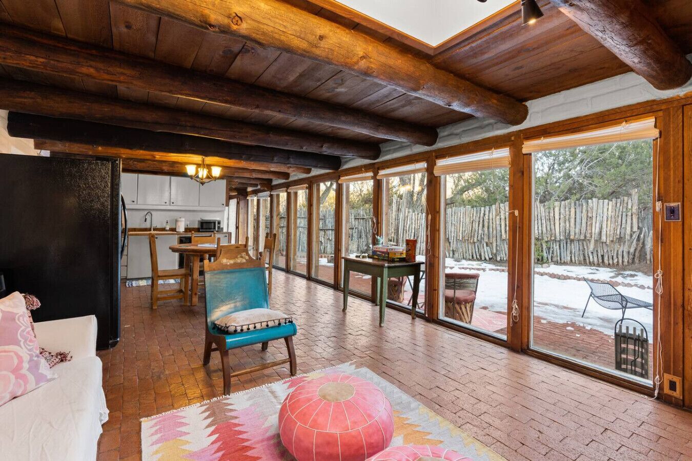 Amplia sala de estar con techo de madera, una mesa de comedor y un ventanal con vistas a un patio trasero cercado.