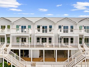 A multi-story building with balconies, a covered lower level, and a clear sky.