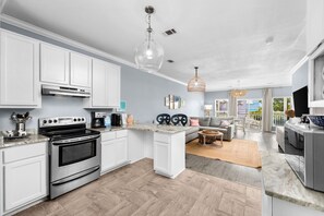 A modern kitchen with white cabinets, a stainless steel oven, and a dining area with a sofa and table.