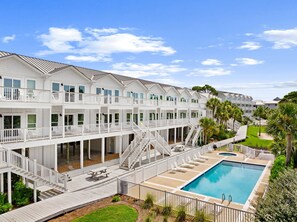 A multi-story hotel with balconies, a pool, and a well-maintained lawn.