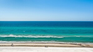 Une plage à l’eau turquoise et limpide, bordée d’un rivage sablonneux.