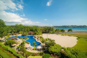 A resort with a large swimming pool, a sandy beach, and a view of the ocean. - Bella Vista 4A 3 bdrs ocean view in Los Suenos (Playa Herradura)