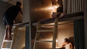 A multi-level bunk bed room with wooden ladders, a light fixture, and a curtain. - Slack BnB - Hostel (Liuqiu)