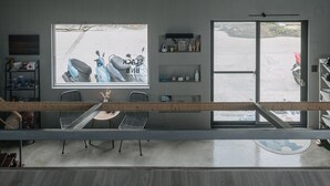 A modern interior with a large window, seating area, and a ceiling fan. - Slack BnB - Hostel (Liuqiu)