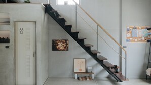 A spacious interior with a staircase, a painting, and a bulletin board. - Slack BnB - Hostel (Liuqiu)