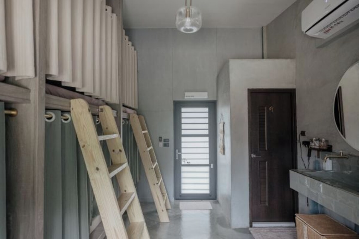 A hallway with a wooden ladder, a door, and a bathroom with a mirror and sink.